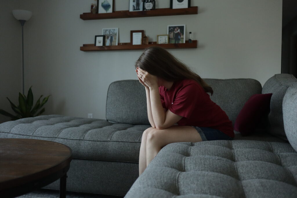 a woman sitting on a couch with her hands covering her face